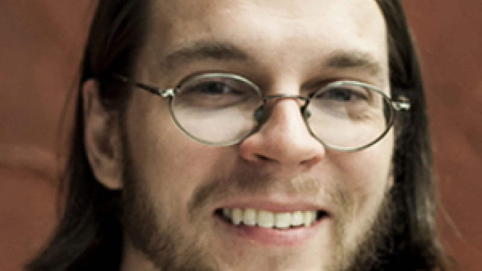 Chris Orban smiling with brown background