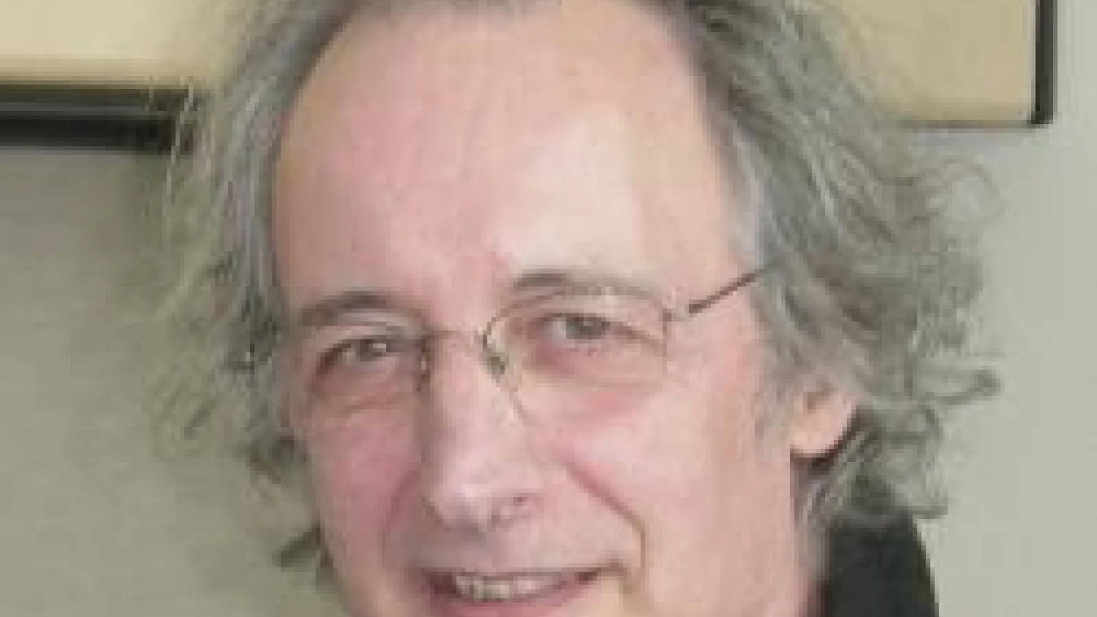 Pierre Agostini smiling with blank wall in the background