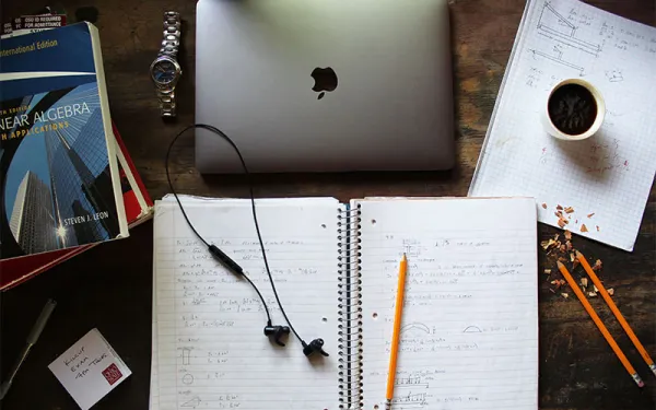 study materials, including notebook, computer, pencils, books, and coffee
