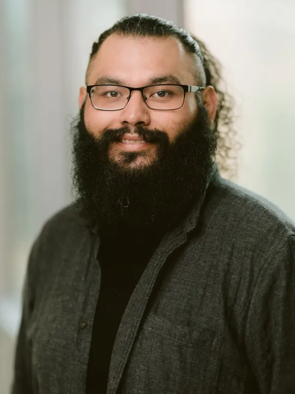 Headshot of Dennis smiling with bright background.