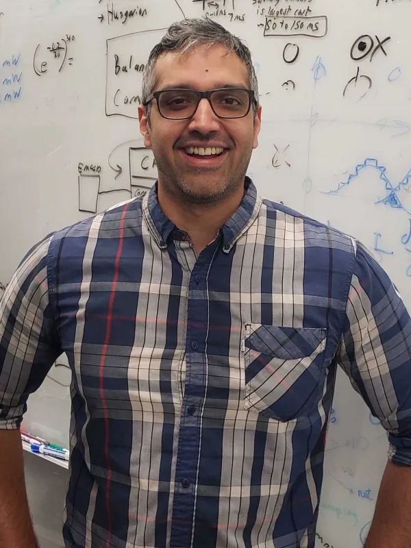 Kevin Singh smiling in front of a whiteboard with hands on hips