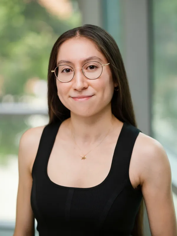 Person wearing a black shirt in front of a green background.